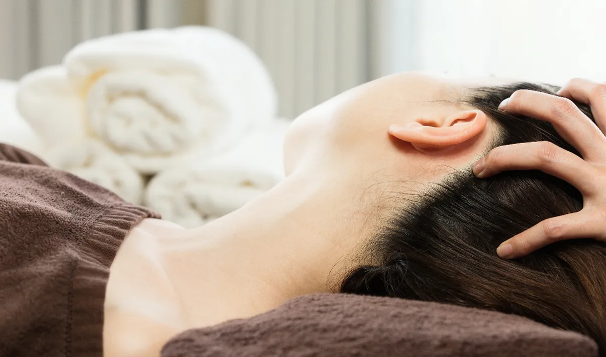 Client détente lors d'un soin des oreilles et massage du cuir chevelu au salon.