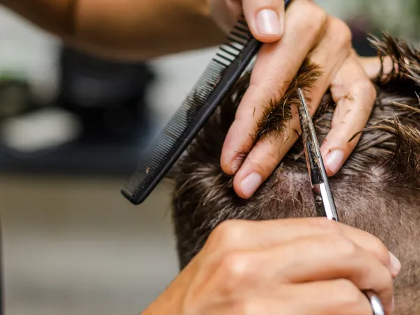 Coiffeur coupant et taillant les cheveux avec précision et soin.